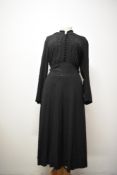 An early 1940s Art Deco black day dress, having self covered buttons and metallic thread detail to