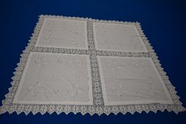 An antique white bed cover, having raised floral embroidery, cutwork edged in pale pink, ladder work
