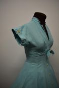 A 1950s textured cotton day dress in aqua blue, with faux buttons to front and cuffs and bow to