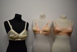 Three vintage 1950s bullet bras, two pale pink and one cream.