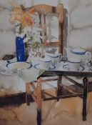 After Richard Akerman (20th Century), a pair of coloured prints, Still life displays on chairs,