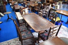 A dark stained Ercol refectory style dining table and set of eight ladder back dining chairs