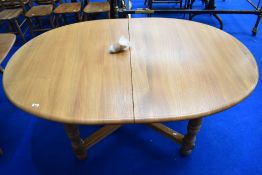 A modern Ercol oval extending dining table having turned legs and X stretcher