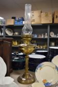 An early 20th century brass oil lamp with glass chimney.