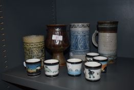 A selection of Ambleside pottery tankards and egg cups, including frog, loch Ness monster and