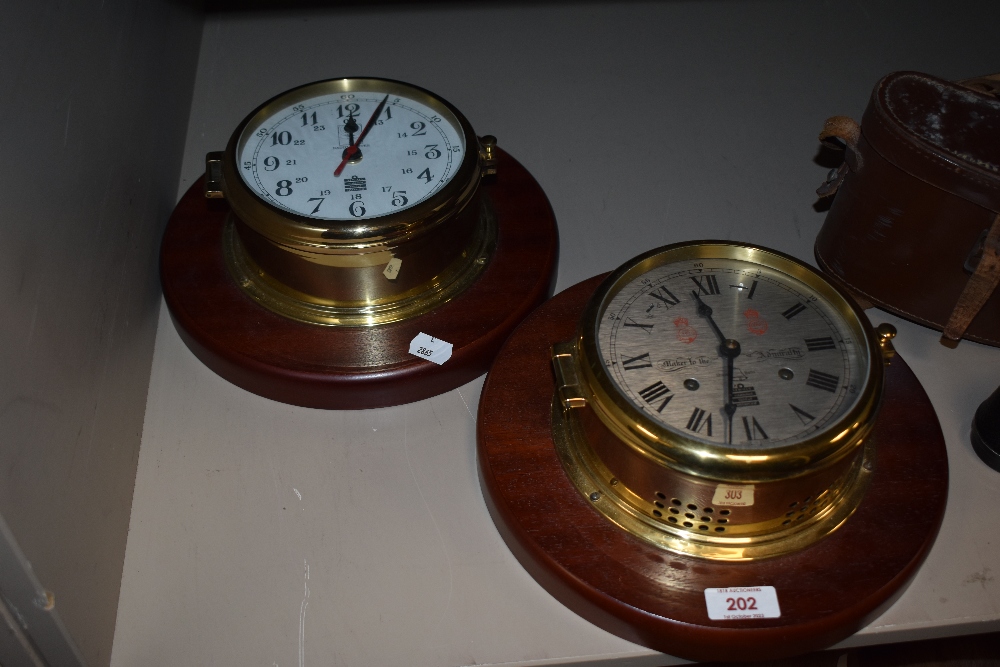 Two 20th century ship clock style wall clocks, mounted on mahogany bases with brass cases.