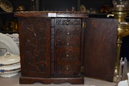 A 19th/early 20th century carved oak miniature cabinet, having five internal drawers and compartment