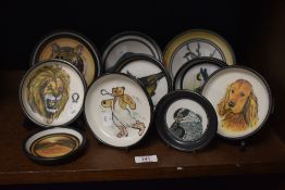 A collection of Ambleside pottery plates, including cocker spaniel, lion and heron.