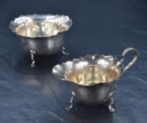 An Edwardian silver sugar and cream, of dishes circular form with flared and petal shaped rim,