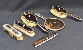A George V silver and tortoiseshell six piece dressing set, comprising a hand mirror, two clothes