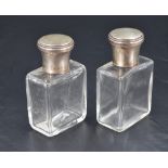 A pair of French white metal topped glass cologne or eau de toilette bottles, the screw-off covers
