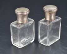 A pair of French white metal topped glass cologne or eau de toilette bottles, the screw-off covers