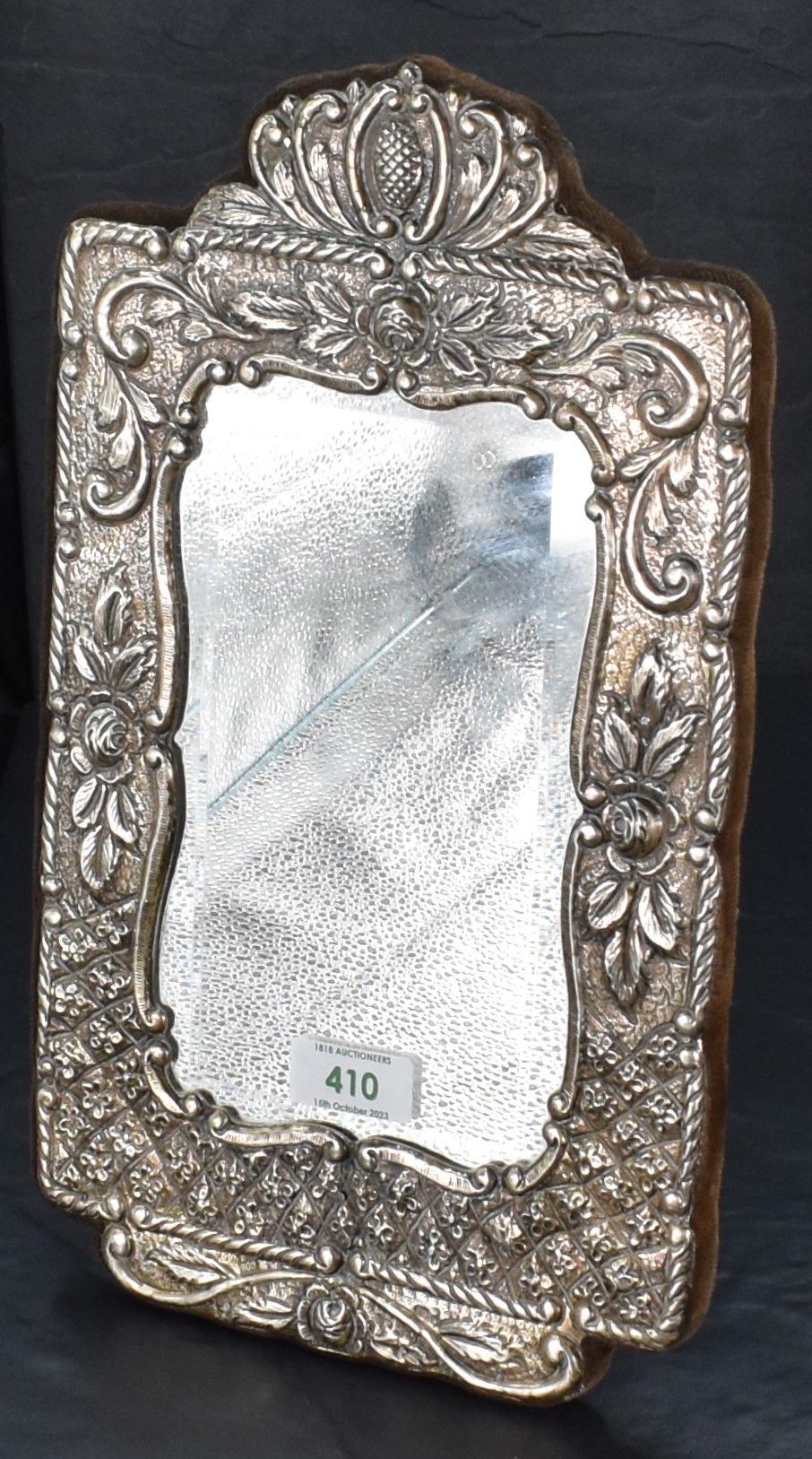 A white metal mounted bevelled glass mirror, of shaped rectangular form, the white metal mount