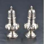 A pair of late Victorian silver pepperettes, of traditional design with pierced finial topped