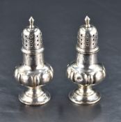 A pair of late Victorian silver pepperettes, of traditional design with pierced finial topped