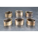 A group of six George V silver napkin rings, of oval form with engine-turned decoration and small