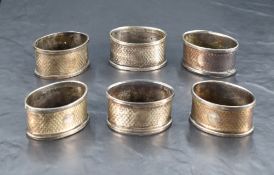 A group of six George V silver napkin rings, of oval form with engine-turned decoration and small