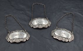 A group of three Queen Elizabeth II silver spirit labels, moulded with shells and scrolls, marked
