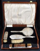 A George V silver mounted travelling dressing/brush set, comprising hand mirror, comb, clothes and