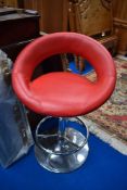 A chrome and red vinyl bar stool
