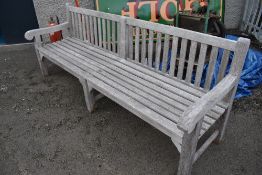 A traditional teak garden bench of very long proportions (one of two) length approx 240cm