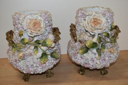 Two 19th century continental porclelaine flower encrusted vases, with cherubs amongst roses to front