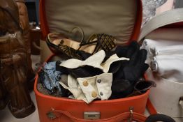 A red leather vanity case containing ladies garments and accessories, gloves, high heeled shoes, and