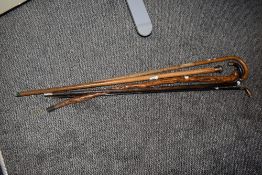 An assorted collection of walking sticks and canes, two with clearly stamped silver handles, plus