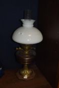 A Victorian oil lamp, having a milk glass shade above an amber glass reservoir, and measuring 59cm