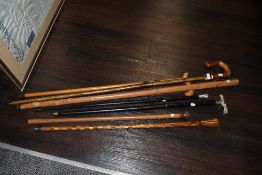 A selection of vintage walking sticks, canes and a staff, including hallmarked silver topped cane.