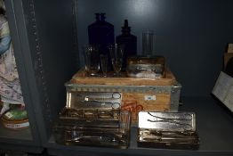 A collection of vintage medical/surgical equipment, including measuring receptacles and blue glass
