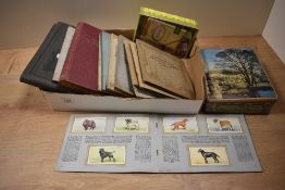 An assorted collection of cigarette cards, displayed in albums and loose