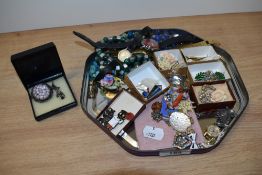 A tray of miscellaneous costume jewellery and badges, including wedding cake beads, wristwatches,