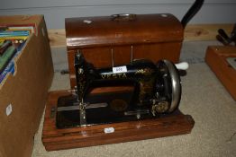 An antique Vesta crank handled sewing machine with bentwood case, serial number 1763409.