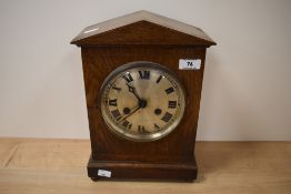 An Edwardian oak cased mantel clock having silvered roman numeral dial
