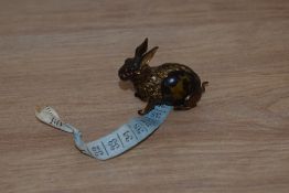 A Victorian cast metal and faux tortoiseshell novelty tape measure in the form of a rabbit.