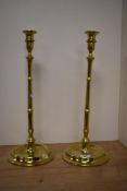 Two tall antique brass candlesticks, having knopped stems and dished foot.
