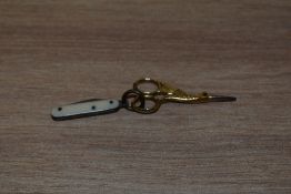 A miniature pair of gold tone sewing scissors in the form of a stork, with boned handled knife