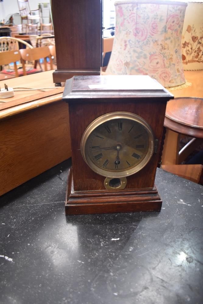 An oak cased mantel clock with brass roman numeral dial