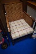 An early 20th Century mahogany framed easy armchair having canework panels and later tweed