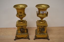 Two ormolu clock garnitures, of campana urn form, both having rose decoration, clawed feet with lion