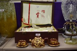 A Chinese red ware tea set in case, having gilt highlighted dragon decoration.
