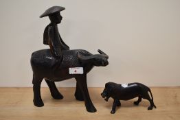 A carved Chinese hardwood study of a man riding a water buffalo and a similar carved lion.