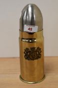 A brass artillery shell shaped cigarette dispenser, having coat of arms to side and polished steel