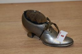 A vintage metal pincushion in the form of a Victorian shoe.