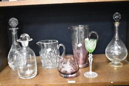 Three glass decanters, a pink tinged water jug, a cut glass jug, a pink tinged vase with etched