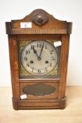 An early 20th century oak cased mantel clock, having carved decorations, brass spandrels to dial,