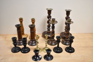 An assorted collection of candlesticks, turned wood candlesticks and ebonised candlesticks