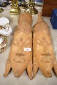 Two light wood Indonesian wall mounted masks.