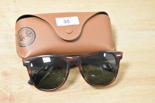 A pair of sunglasses, with case, bearing Ray-Ban branding.